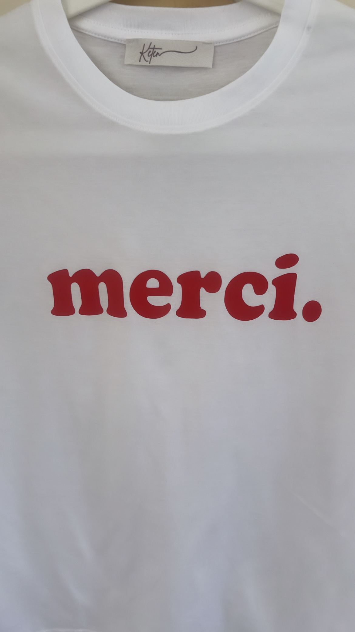  biały T-shirt z czerwonym napisem "Merci"  to idealne uzupełnienie codziennych stylizacji. Wykonany z wysokiej jakości bawełny.